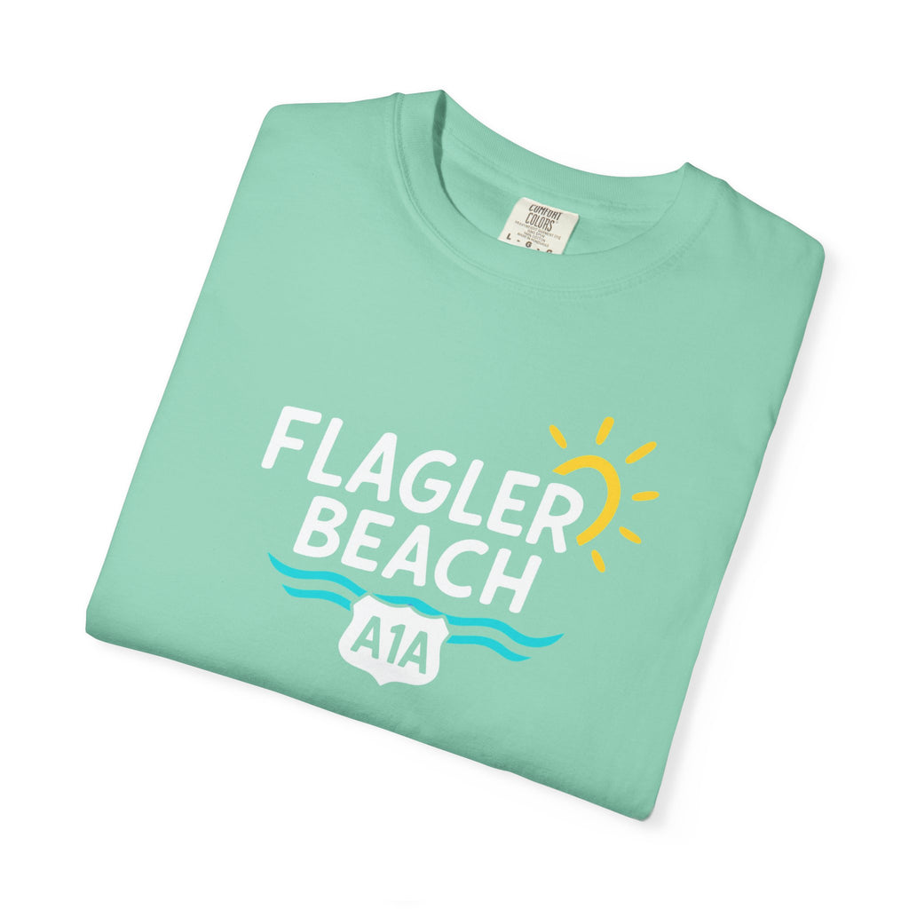 Folded mint green t-shirt with 'Flagler Beach A1A' text and graphics on a white background