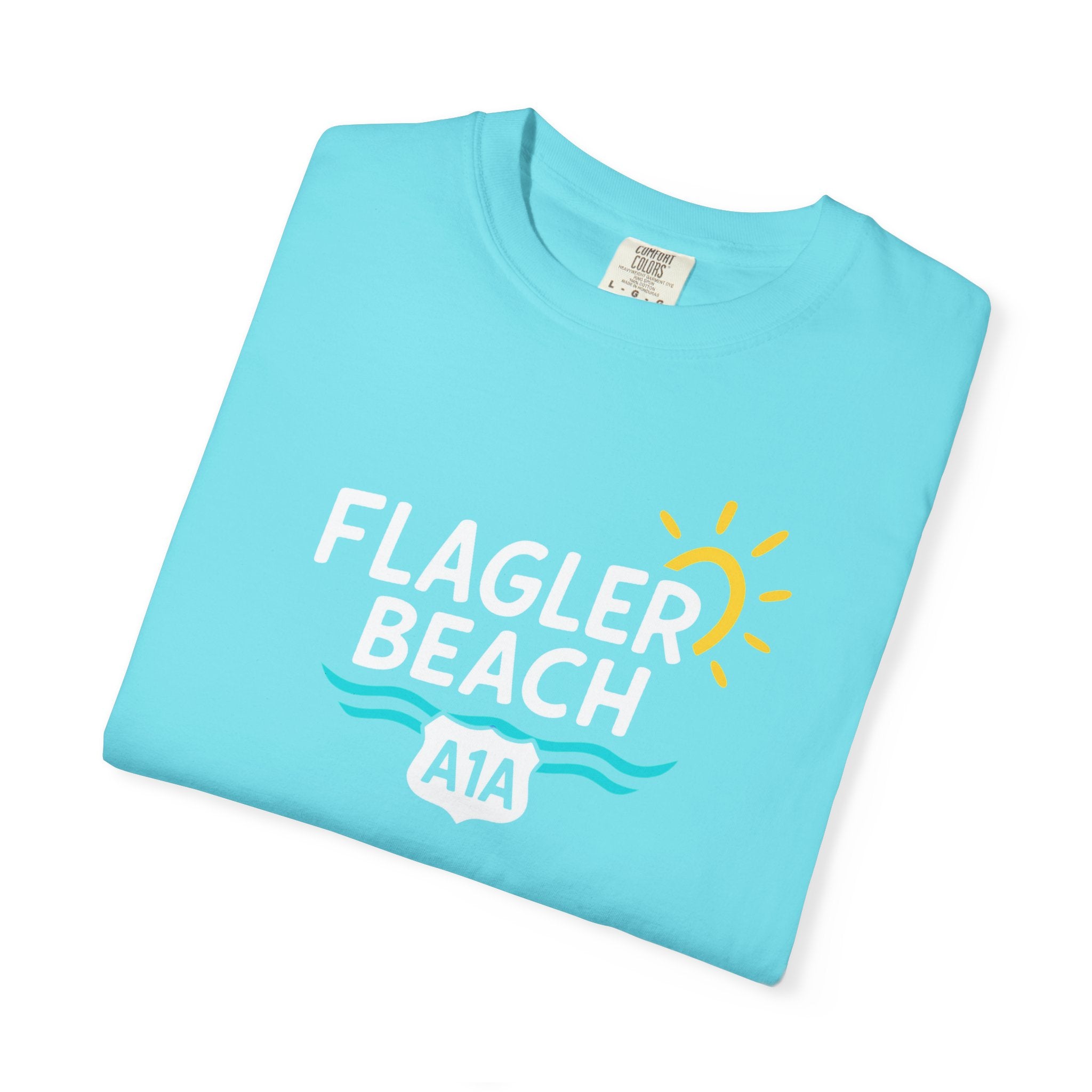 Folded light blue t-shirt with 'Flagler Beach A1A' text and graphics on a white background