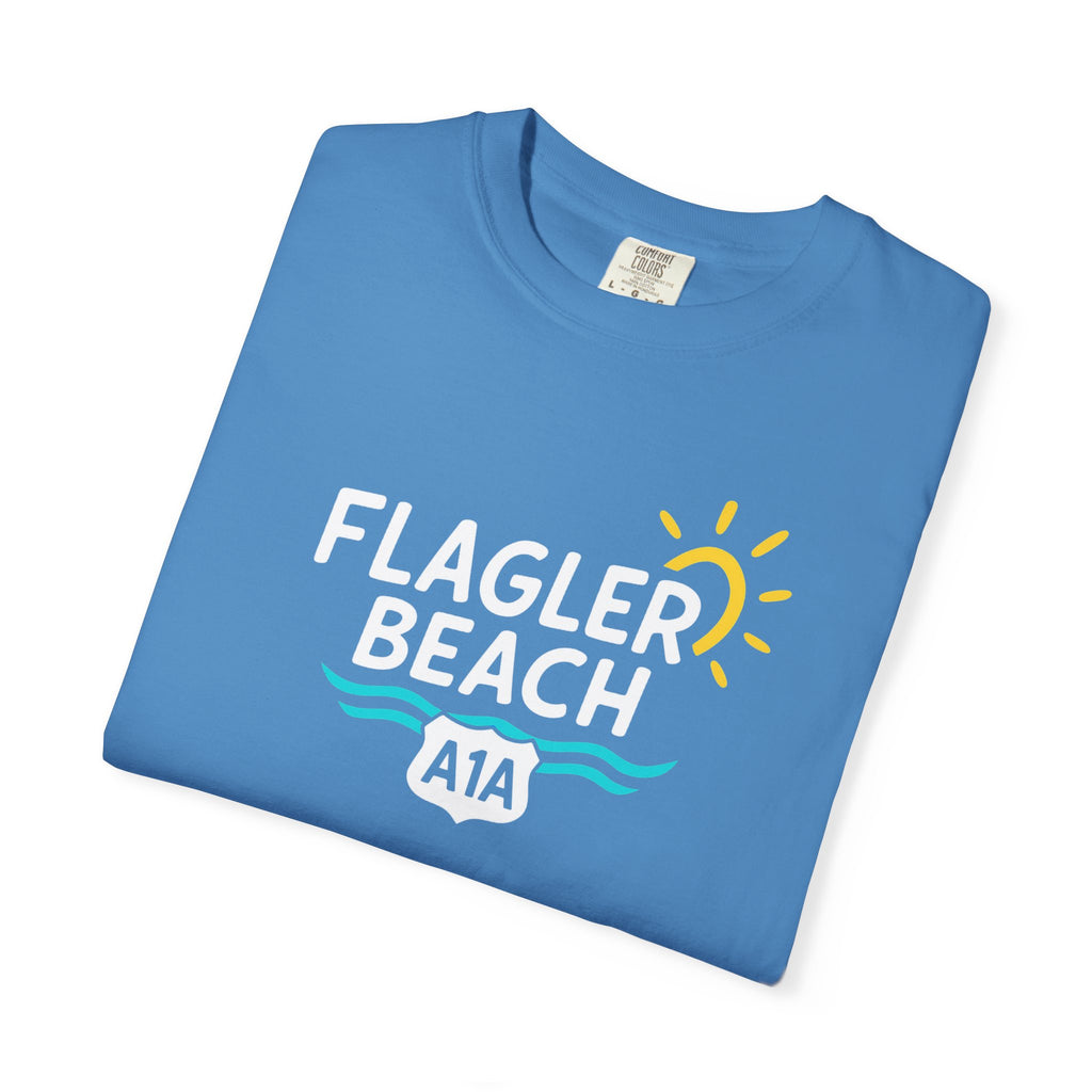 Folded blue t-shirt with 'Flagler Beach A1A' text and graphics on a white background