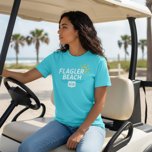 Woman wearing a turquoise 'Flagler Beach' t-shirt sitting in a golf cart on a beach.