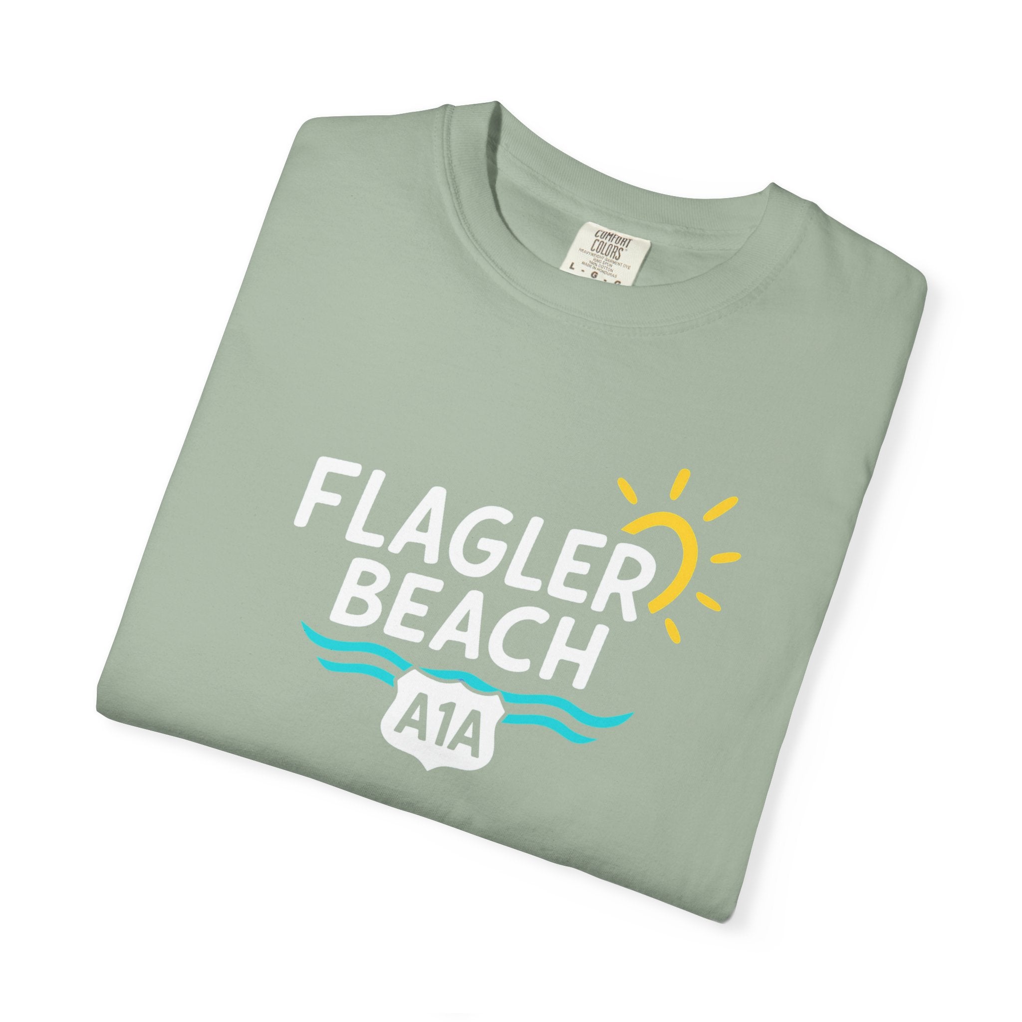 Folded green t-shirt with 'Flagler Beach A1A' text and graphics on a white background