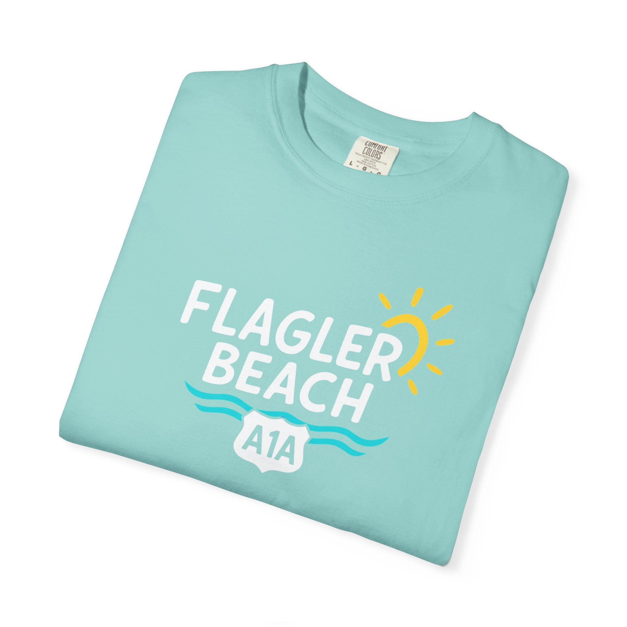 Folded light blue t-shirt with 'Flagler Beach A1A' text on a white background