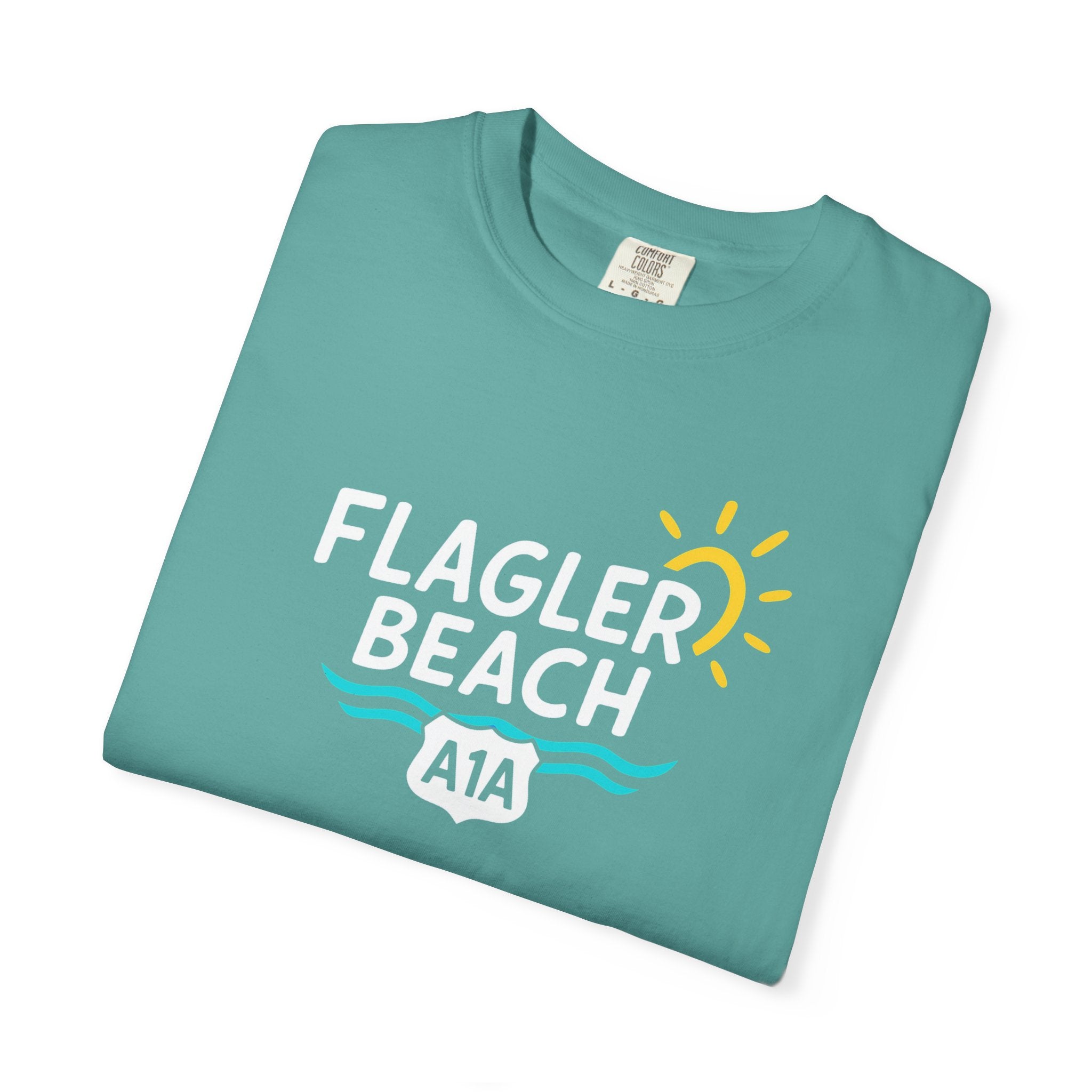 Folded teal t-shirt with 'Flagler Beach A1A' text and graphics on a white background